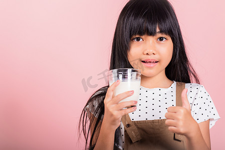 亚洲小孩 10 岁笑着拿着牛奶杯喝白牛奶，竖起大拇指