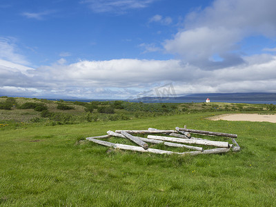 冰岛夏日风景，郁郁葱葱的绿草草甸、原木、海平线小屋和蓝天白云背景