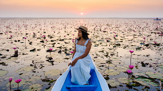 泰国乌隆他尼的红莲海 Kumphawapi 满是粉红色的花朵，亚洲女性在一艘船上。