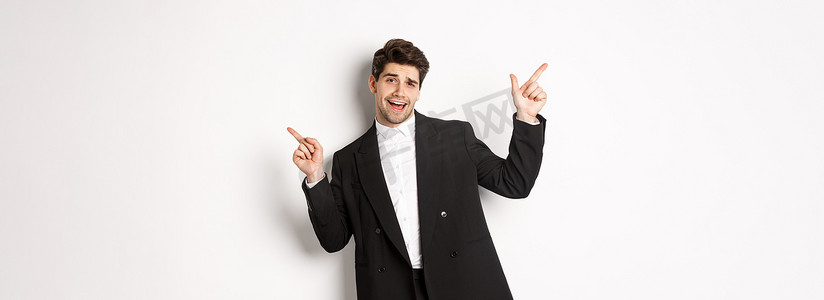 穿着黑色西装跳舞和聚会的帅哥，手指横着，展示两条促销横幅，站在白色背景下