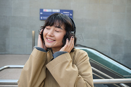 快乐女人的画像，戴耳机的韩国女孩，戴耳机听音乐，享受耳机的声音，笑着笑