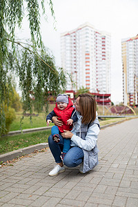 散步摄影照片_快乐的年轻父母和她的小儿子在城市公园散步