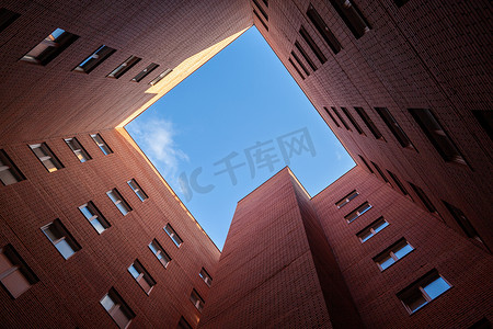 高层窗户摄影照片_蓝天背景下的砖砌高层新方形房屋。