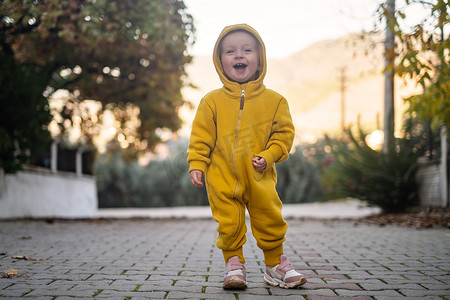 一个小孩穿着黄色连身裤在户外散步。