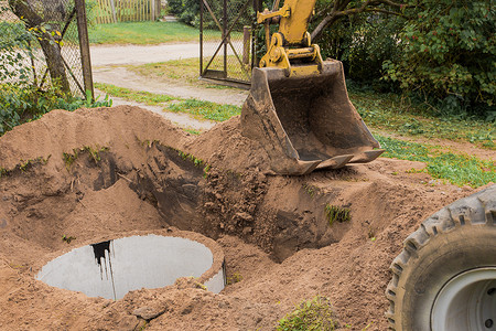 水泥桶摄影照片_一桶带有一堆沙土的挖掘机在工业区埋下水道混凝土环