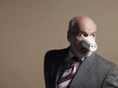 猪鼻子摄影照片_商人戴着塑料杯作为猪鼻子