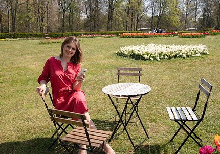 一个穿着红色裙子的年轻美女在春天的公园里玩耍并自拍