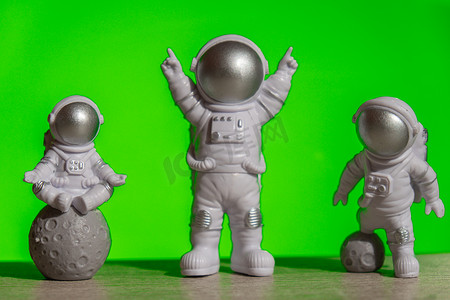 色度摄影照片_三塑料玩具宇航员在绿色色度键背景模板模拟复制空间。