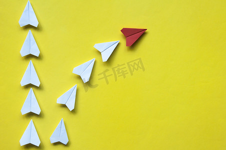 红色纸飞机折纸与其他白色飞机一起在黄色背景上留下，带有可定制的文本或想法空间。