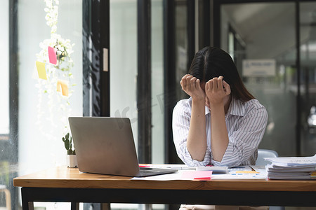 亚洲女性在笔记本电脑上工作时压力很大，疲惫的亚洲女商人在办公室头痛，工作时感觉不舒服