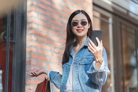9块9限时摄影照片_亚洲时尚女性提着购物袋在购物中心散步，同时进行限时促销