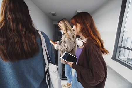 白人女学生的侧视特写，在大学宿舍里用他们的数字设备行走