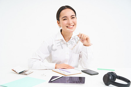 成功女商人的肖像，工作场所的办公室经理，坐在数字平板电脑和她的工作文件上，戴着眼镜，对着镜头微笑
