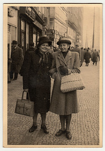 复古照片显示妇女沿着街道走。