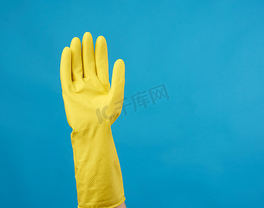 一只手势摄影照片_一只女性手上穿着用于清洁的黄色橡胶手套，蓝色
