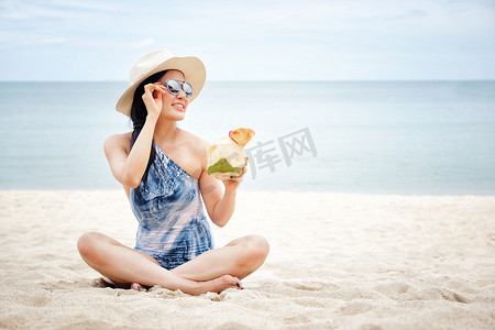 新鲜椰子水摄影照片_海滩上有新鲜椰子水的快乐女人