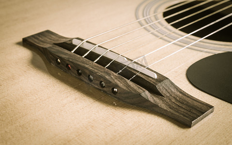 木吉他摄影照片_带木吉他弦的木桥和鞍座和音孔
