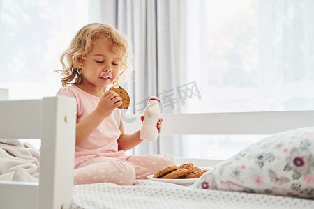 坐在床上，吃饼干喝牛奶。