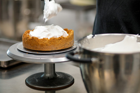 酥皮碎摄影照片_糕点师设计师用抹刀在馅饼皮中填入柠檬味蛋白酥皮慕斯奶酪奶油