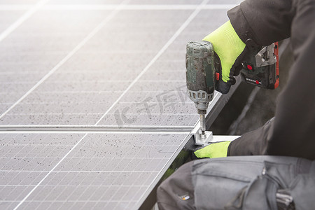 超高频模块摄影照片_太阳能电池板安装人员使用铝制紧固件和无绳电钻将模块拧在一起。