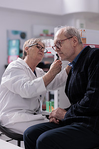 药房员工用耳镜检查老人耳朵
