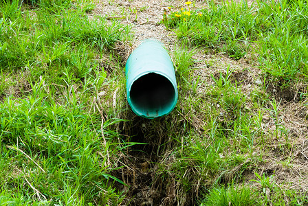 涌现从草地的塑料绿色排水管