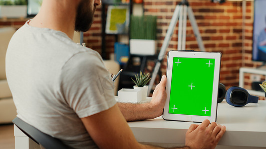 垂直手持带绿屏模板的数字平板电脑的年轻人