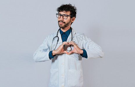 英俊的医生用手做心形手势。