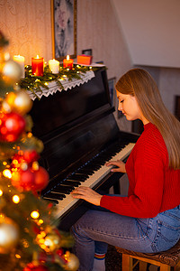 客厅钢琴摄影照片_在家装饰的客厅附近弹钢琴的金发小女孩