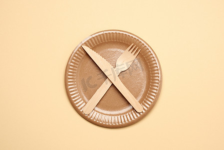 纸盘摄影照片_空的棕色纸盘和木刀叉，物品交叉
