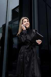 一位女商人手里拿着电话，在商务中心的背景下通过手机连接与合作伙伴交谈