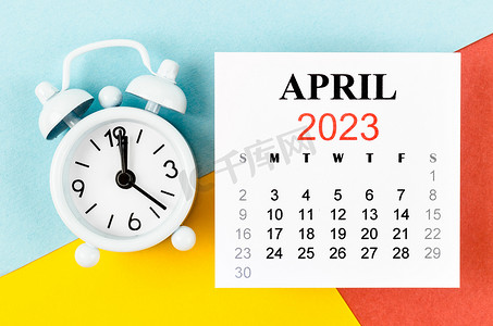 2023年4月摄影照片_2023 年 4 月日历年，彩色背景闹钟。