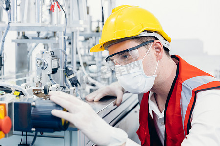 专业工程师男性服务先进技术机器，在工厂科学实验室配备清洁保健用品面罩和防护安全布。