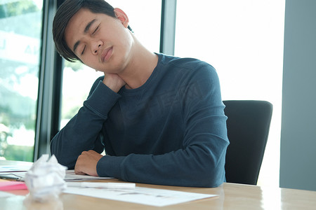 男人感到疲倦，沮丧，因为桌上皱巴巴的碎纸辛勤工作而感到压力。