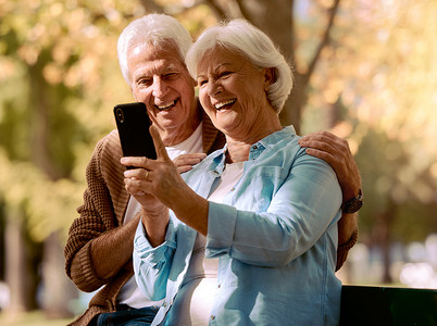 老年夫妇、手机自拍和快乐的微笑、在户外公园、夏天和长椅上的社交媒体图片中爱和放松。