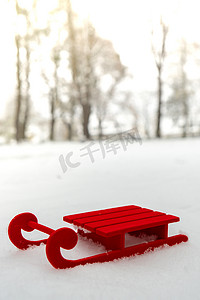 在美丽的冬日雪背景上的小红色雪橇。