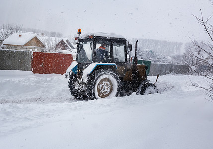 厚厚的雪摄影照片_一辆小型拖拉机从雪中清除道路