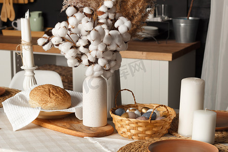 装饰彩蛋摄影照片_彩蛋放在篮子里，面包放在装饰有复活节装饰的桌子上。
