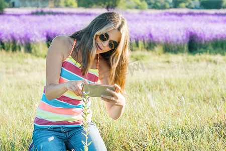 花卉植物摄影照片_在大自然中行走的少女在手机上拍摄花卉植物