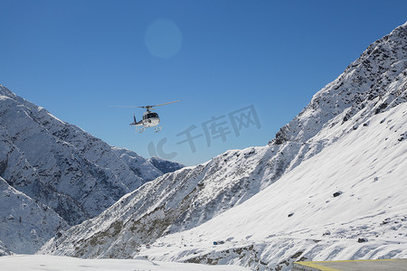 直升机在喜马拉雅山白雪覆盖的山谷中飞行。