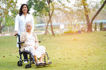 医生在护理医院病房帮助和照顾坐在轮椅上的亚洲老年或老年老妇人患者：健康强大的医疗理念