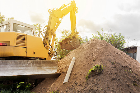 带铲斗的液压活塞系统挖掘机在工业现场卸载一大堆土地。