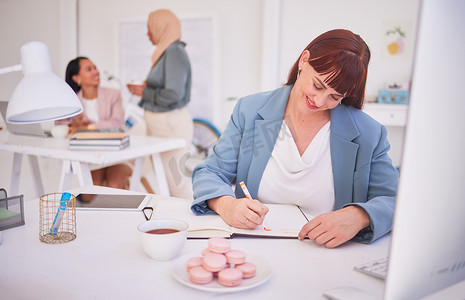 商务、女性和在茶歇时在办公室里吃零食和规划日程的同时写书。