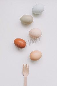 餐具包装摄影照片_自然色调和颜色的鸡蛋和木叉，白色背景的竹餐具。