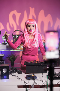 粉红色头发的艺术家在工作室里玩得开心，同时使用专业调音台演奏技术歌曲