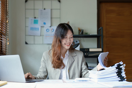 财务报表分析报告摄影照片_一位深思熟虑的亚洲女商人的肖像，她正在使用办公桌上的电脑查看财务报表并制定营销计划