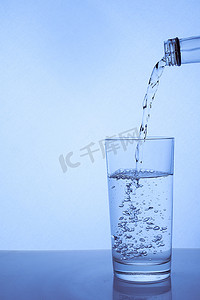菜单黑金摄影照片_新鲜干净的水从瓶子里倒进玻璃杯里。