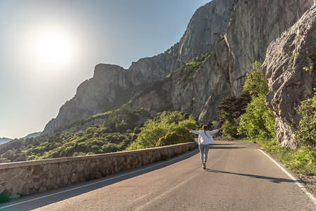 一名妇女沿着山区中间的柏油路奔跑。