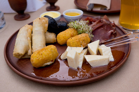 粘土盘上的啤酒小吃：bastruma、feta 奶酪、面糊中的奶酪、蜂蜜和芥末。