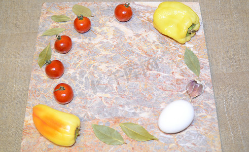 大理石表面上的蔬菜和鸡蛋，有自由空间：樱桃番茄、甜椒、大蒜和月桂叶
